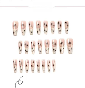 Detailed view of long ballerina press-on nails with nude pink base and black starburst patterns