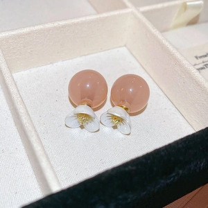 Macro detail of elegant double-sided floral stud earrings with pink resin beads