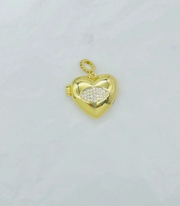 Macro detail of a heart-shaped locket pendant with gold finish and zircon eye design