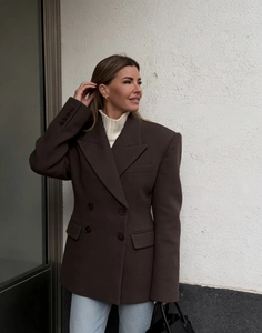 Detail of dark brown double-breasted blazer with classic lapels and flap pockets