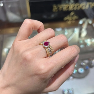 Detailed shot of an emerald-cut ruby ring with gold filigree and diamond halo
