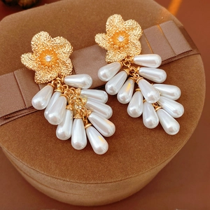 Vue macro de boucles d'oreilles fleur dorée avec perles en goutte sur boîte en velours