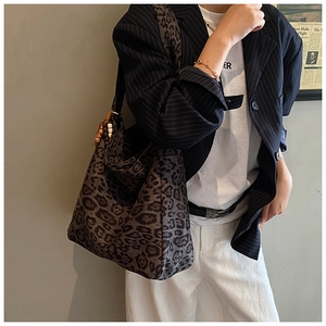 Detail view of large leopard print tote bag featuring wooden bead decor on wide shoulder strap