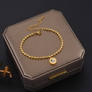 Detailed macro view of gold beaded bracelet with Roman numeral zircon pendant