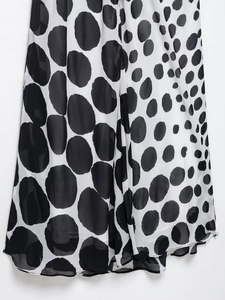Detail shot of black and white polka dot chiffon dress showing hemline and fabric texture