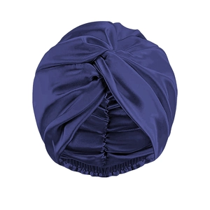 Dettaglio del turbante in raso blu navy con nodo a torsione e trama a fascia elastica