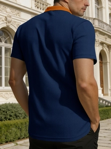 Détail du tissu gaufré bleu marine avec col contrasté orange sur chemise pour hommes