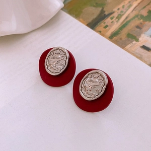 Macro shot of vintage cameo earrings featuring a lady silhouette on a red matte base