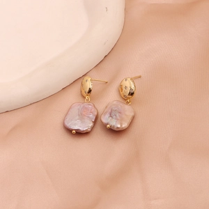 Detailed view of pink baroque pearl earrings with gold zircon studs on champagne silk