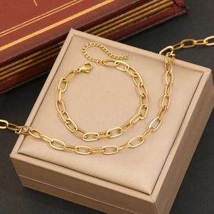 Detailed view of golden chain necklace and bracelet set on a beige jewelry box