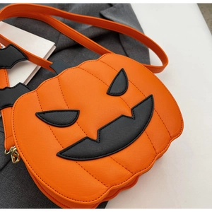 Close-up of orange pumpkin crossbody bag with black jack-o'-lantern face and bat decor