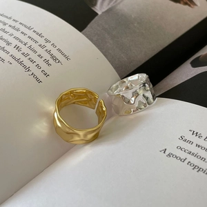 Detail of gold and silver S925 rings with hammered texture resting on a book