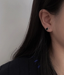 Close-up of heart-shaped black epoxy ear clip with silver metal edges on a model's ear