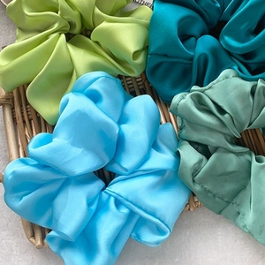 Oversized satin hair scrunchies in multiple pastel colors on a woven bamboo tray