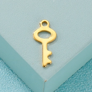 Minimalist gold stainless steel key pendant accessory on a textured blue display stand