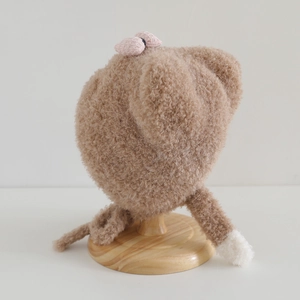 Plush brown bear ear hat for toddler with pink bow and warm chin ties on wood stand