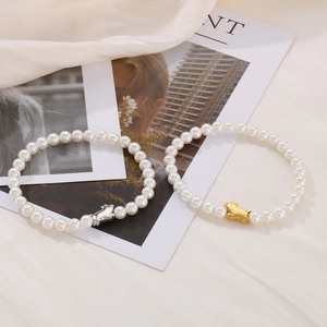 Detail of beaded shell pearl bracelets with gold and silver pig charms on elegant fabric