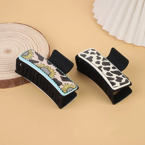 Detail of matte hair claws featuring sunflower leopard and cow prints on wooden stand