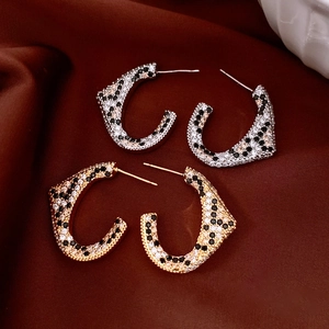 Detailed view of C-shaped leopard style earrings with inlaid crystals on silk fabric