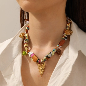 Detail of floral printed silk scarf necklace with golden heart pendant and green beads