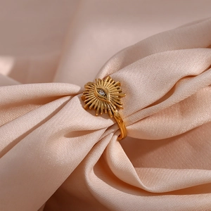 Macro detail of a gold-plated evil eye ring with zircon on pink silk fabric background