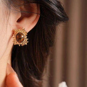 Detail of vintage gold square earrings with brown tiger eye stone on model's ear