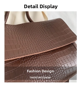 Detail of dark brown tote with crocodile embossed texture and refined edge stitching