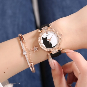 Detail of rose gold cat watch and star charm bracelet set worn on denim fabric