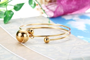 Detailed shot of gold plated stainless steel open bangle with polished ball charms
