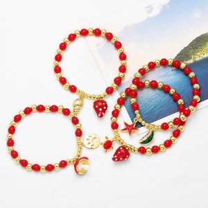 Set of four red beaded bracelets with gold charms like strawberry, mushroom, and shell