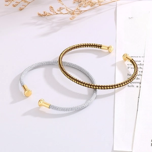 Detail of gold and silver C-shaped braided bangles with cylindrical metal end caps
