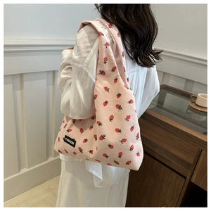 Pink corduroy tote bag with red strawberry pattern shown on model in lifestyle setting