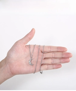 Macro detail of silver moon pendant necklace with irregular hammered texture on hand