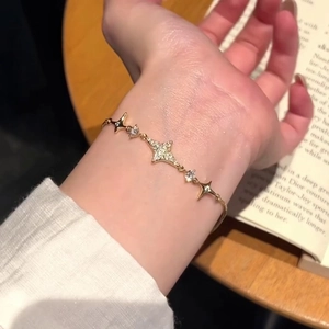 Close-up of 18k gold plated star bracelet with sparkling zircons on a hand with book background
