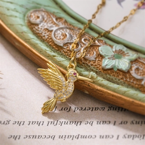 Macro d'un pendentif colibri doré avec zircons blancs étincelants et œil en gemme rouge