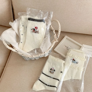 Calze di cotone crema con ricamo a bassotto e volant in una confezione minimalista