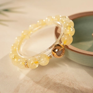 Macro detail of artificial citrine beaded bracelet with gold gourd charm and pavé spacers