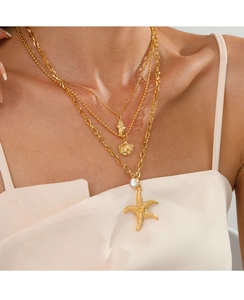 Model wearing a layered gold necklace with starfish, seashell, and pearl pendants