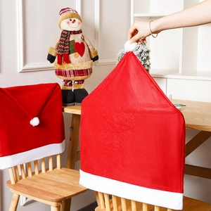 Detail of red plush Christmas chair covers with white fur trim and pom-poms for dining decor