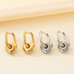 Gros plan de boucles d'oreilles cœur en or 18K et argent sur un tissu en soie élégant