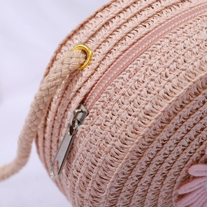 Detail of pink woven straw crossbody bag with secure zipper closure and metal eyelets