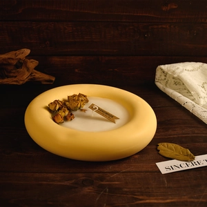 Macro detail of yellow donut-shaped handmade candle with dried flowers and paper label
