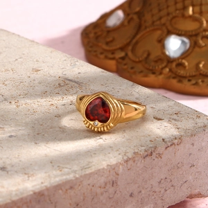 Detail of a vintage 18K gold-plated ring featuring a red heart-shaped zircon and small diamond
