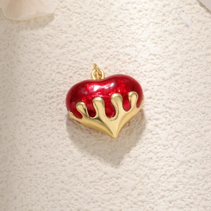 Elegant red heart pendant with gold metal trim displayed on a textured background