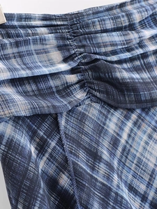 Dettaglio del tessuto a quadri blu e beige con pieghe delicate e cuciture rifinite