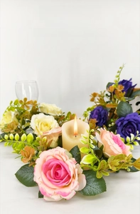 Detailed view of pink and purple artificial rose wreath with lush green leaves