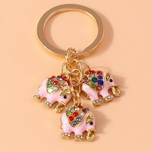 Detail eines goldenen Schlüsselanhängers mit drei rosa Elefanten und bunten Strasssteinen
