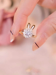 Detailaufnahme eines drehbaren goldenen Hasenrings mit Zirkon und weißer Emaille