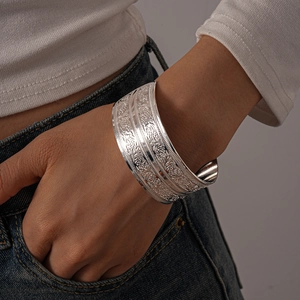 Close-up of wide silver open cuff bracelet with vintage floral ethnic relief patterns