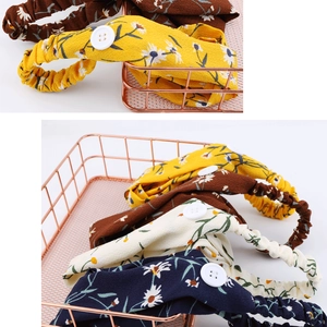 Detail of four daisy print chiffon headbands with white buttons in a gold wire basket